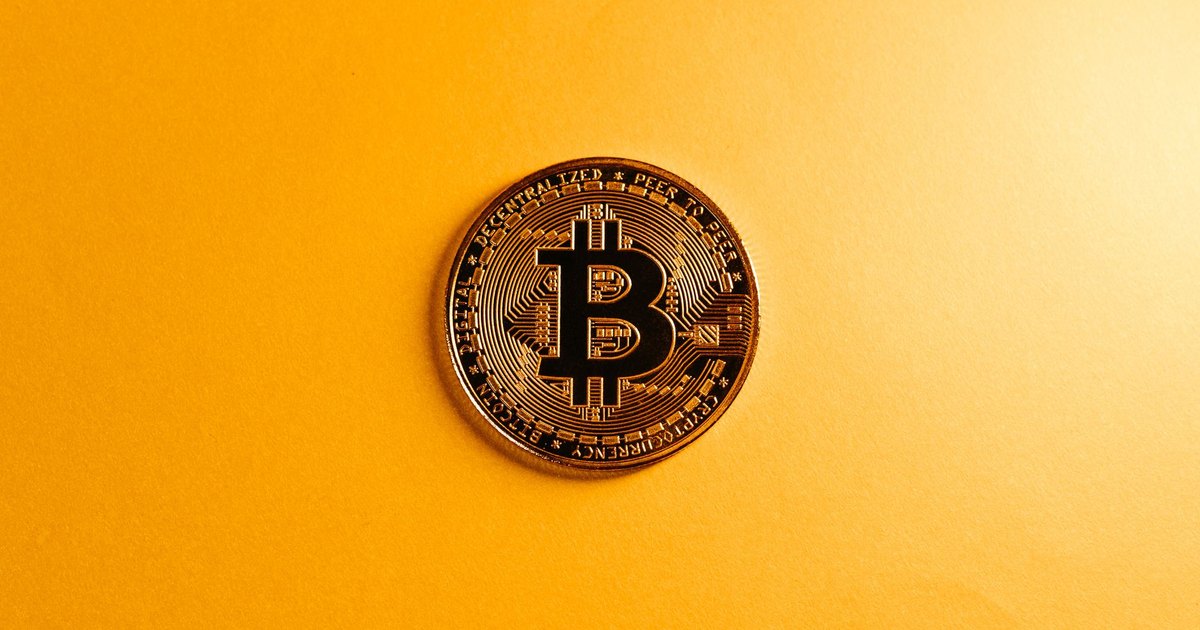 A close-up of a Bitcoin coin on a bright yellow background, symbolizing digital currency.