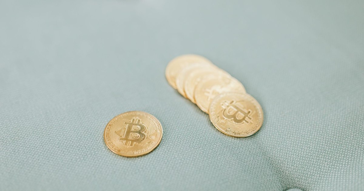 Close-up of gold Bitcoins laid on a soft blue fabric background, representing cryptocurrency wealth.