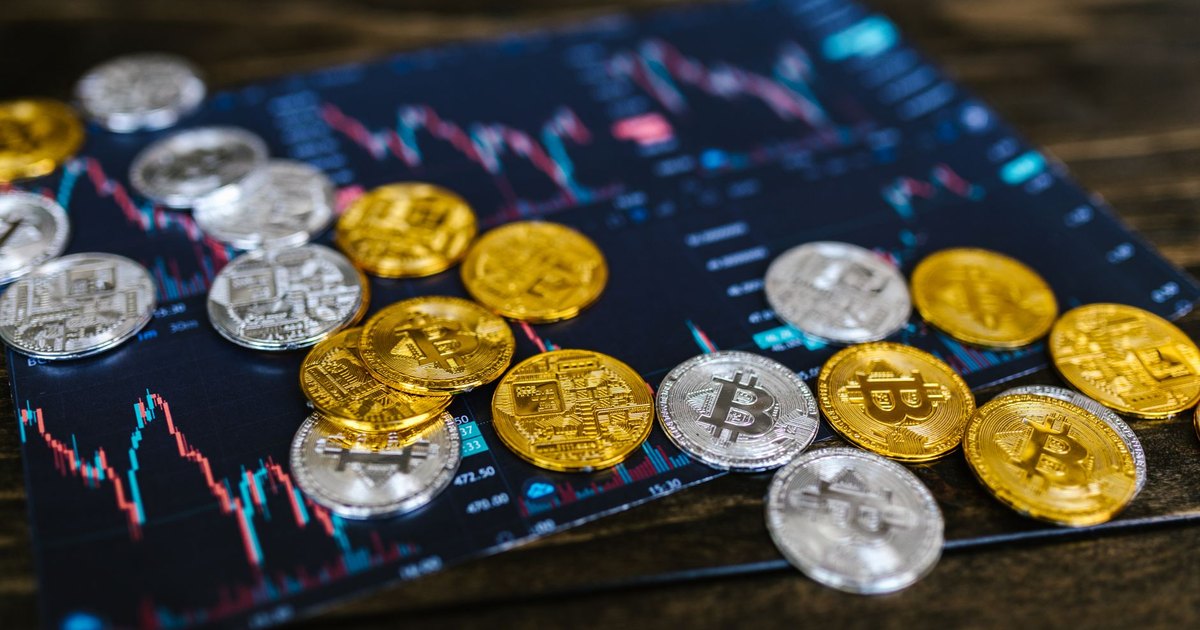 Gold and silver Bitcoin coins on financial graph, symbolizing cryptocurrency trading and digital currency wealth.