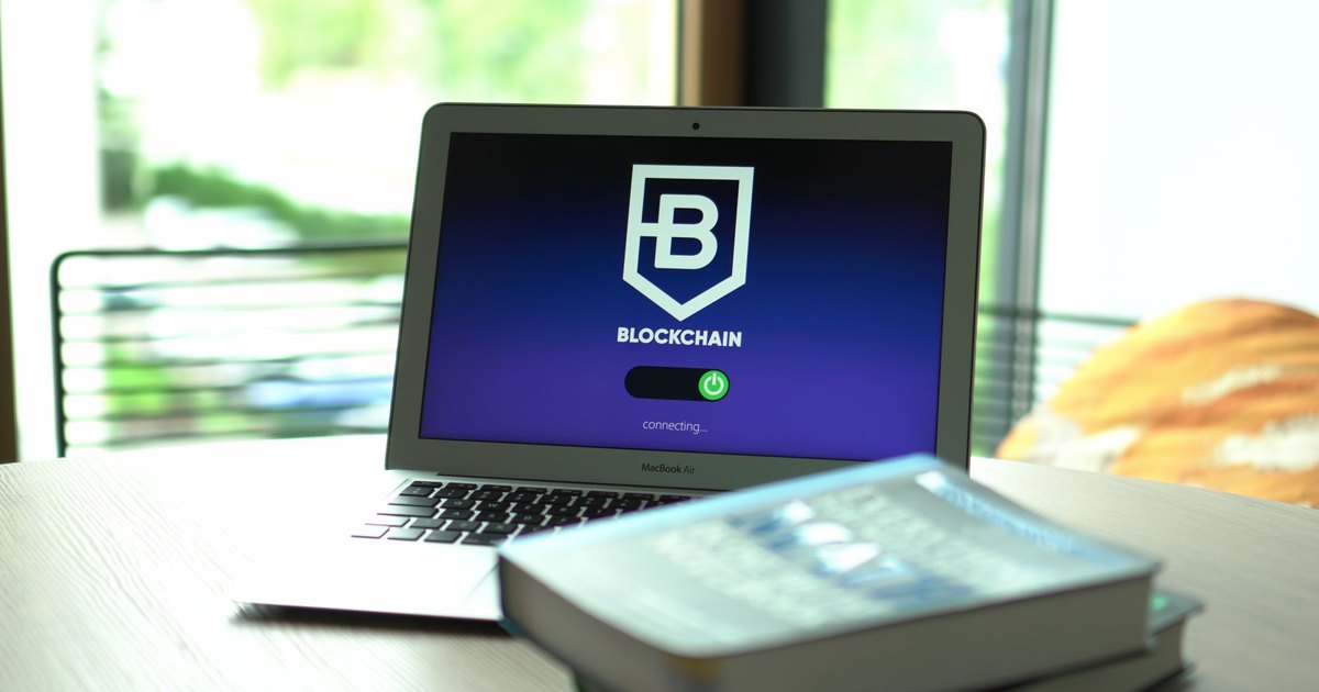 Laptop displaying blockchain connecting screen in modern setting.