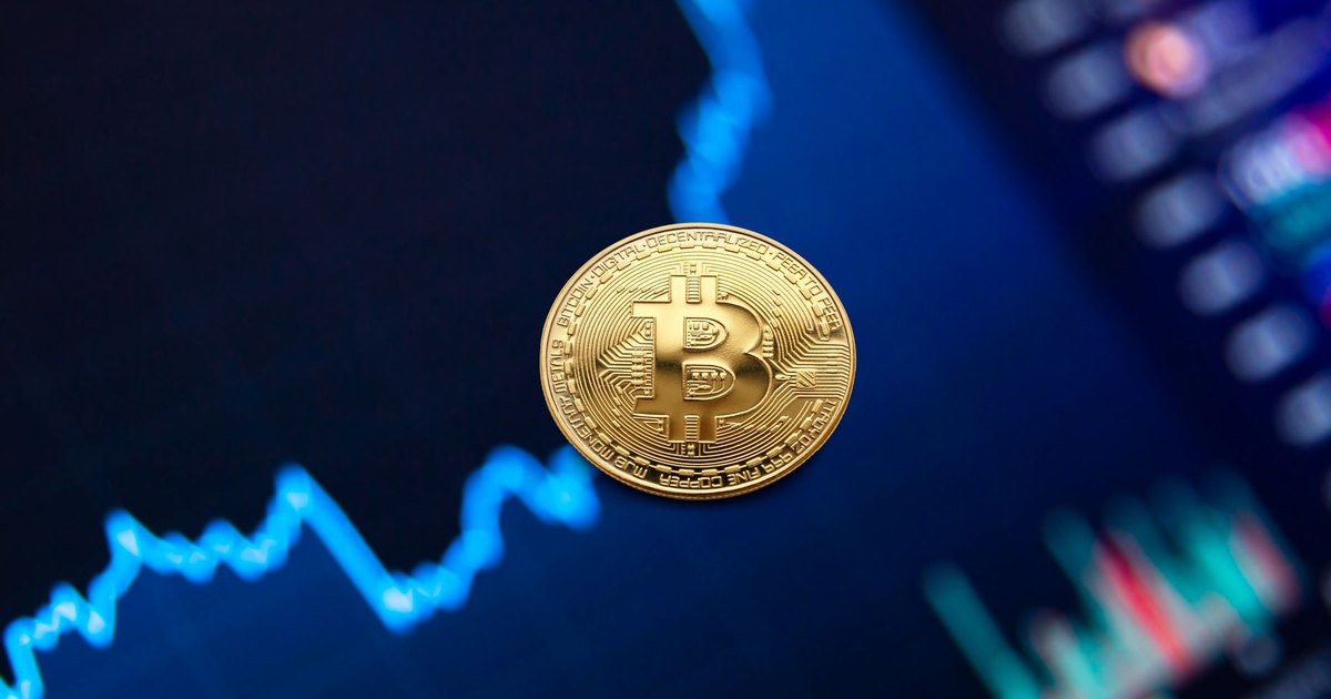 Bitcoin coin on background of monitor with graph of changes in cryptocurrency rates