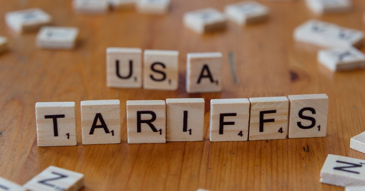 Wooden tiles spelling 'USA' and 'TARIFFS' on a wooden surface symbolizing trade issues.