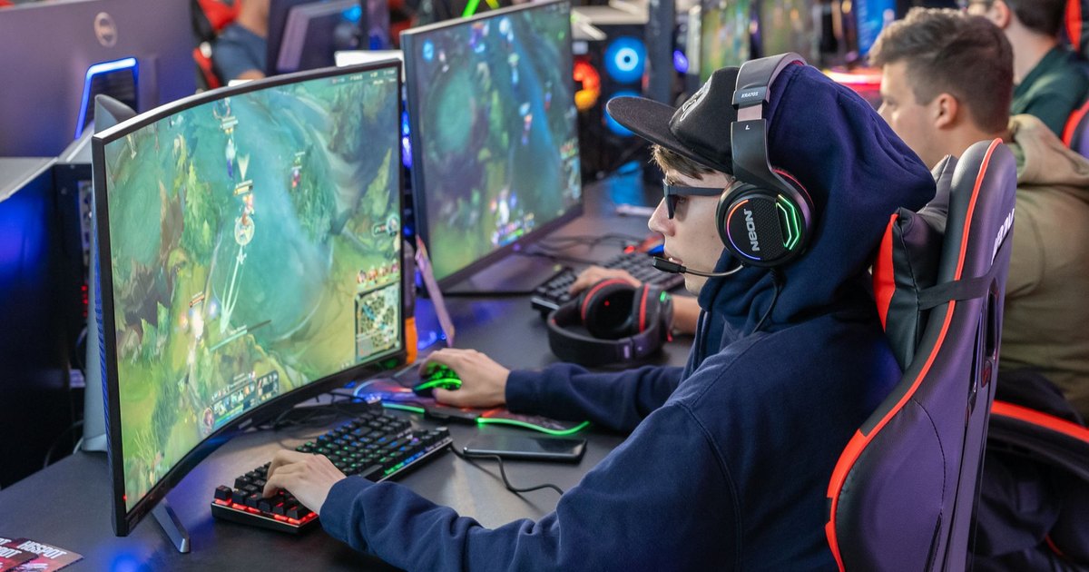 Gamers in an esports tournament playing on high-end gaming setups with monitors, keyboards, and headphones.