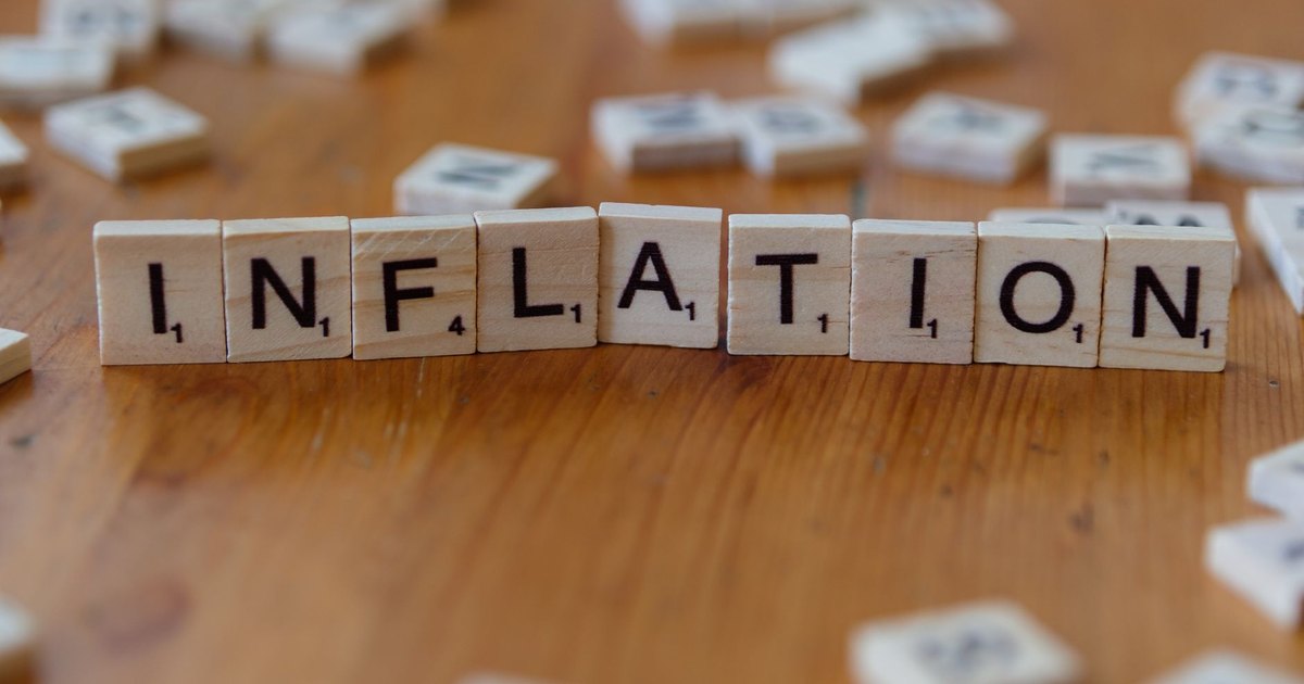 Scrabble letter tiles spelling 'INFLATION' on a wooden table, signifying economic concepts.