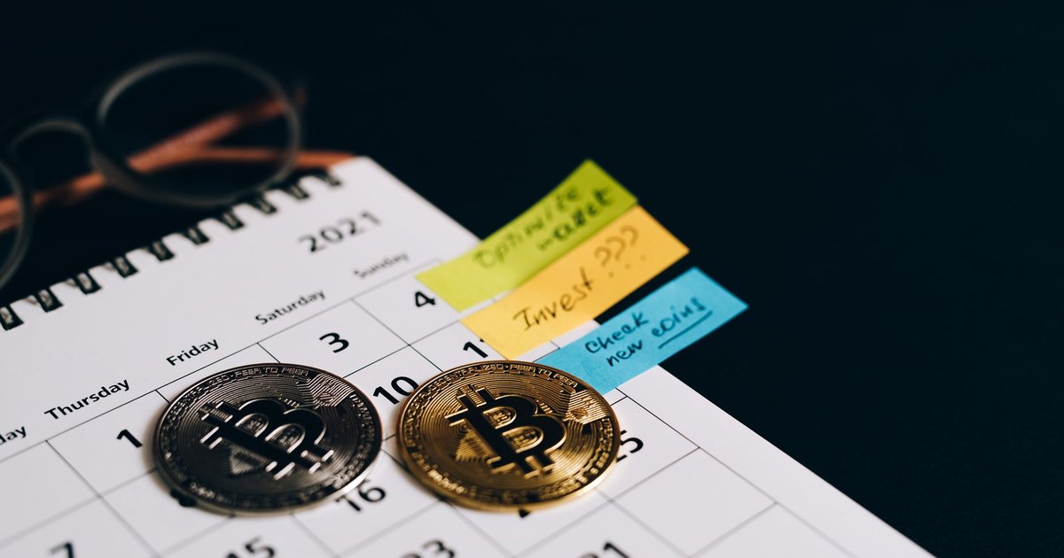 Bitcoin coins placed on a calendar with sticky notes for investment planning.