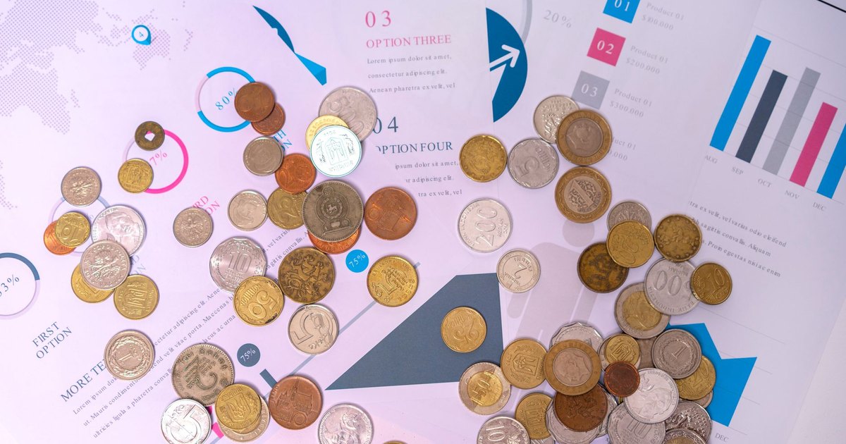 Image of various coins on financial documents with graphs and charts.