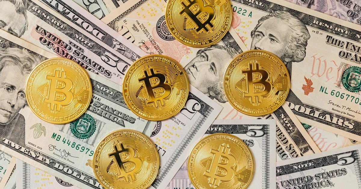 Gold bitcoins placed on a background of US dollar bills representing cryptocurrency and traditional finance.