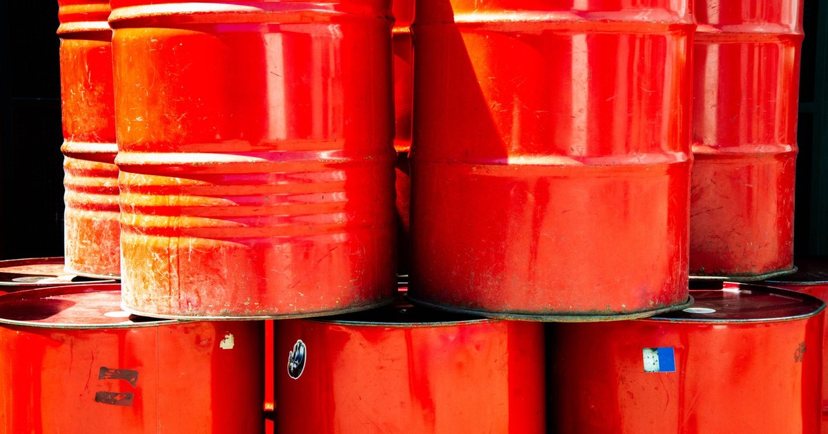 Bright red industrial oil barrels stacked outdoors in daylight, showcasing vivid color and industrial theme.