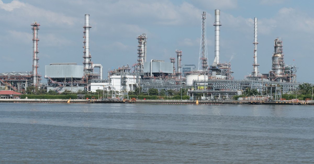 A large oil refinery complex next to the water with cloudy skies.